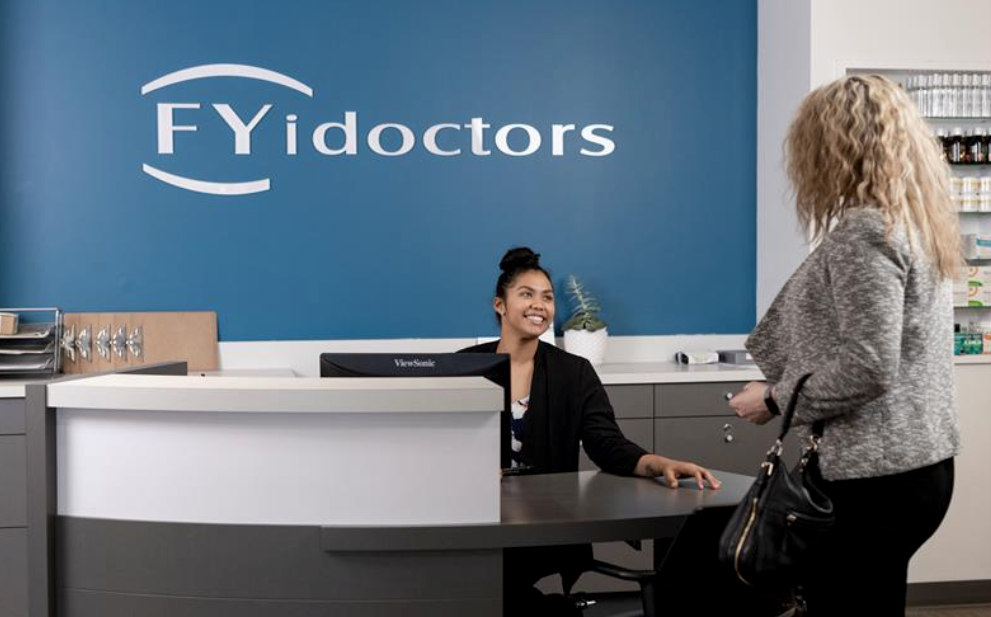 Une réceptionniste FYidoctor répond chaleureusement à un client sans rendez-vous avec le sourire dans l'une des cliniques ophtalmologiques Fyidoctor