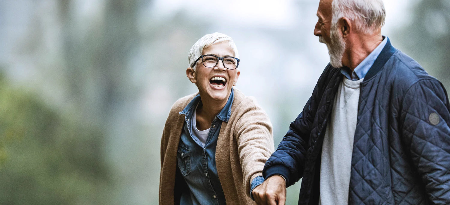 Aged couple putting on glasses laughing along the path
