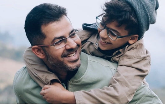 Un papa portant son jeune enfant sur son dos. L'enfant met des lunettes