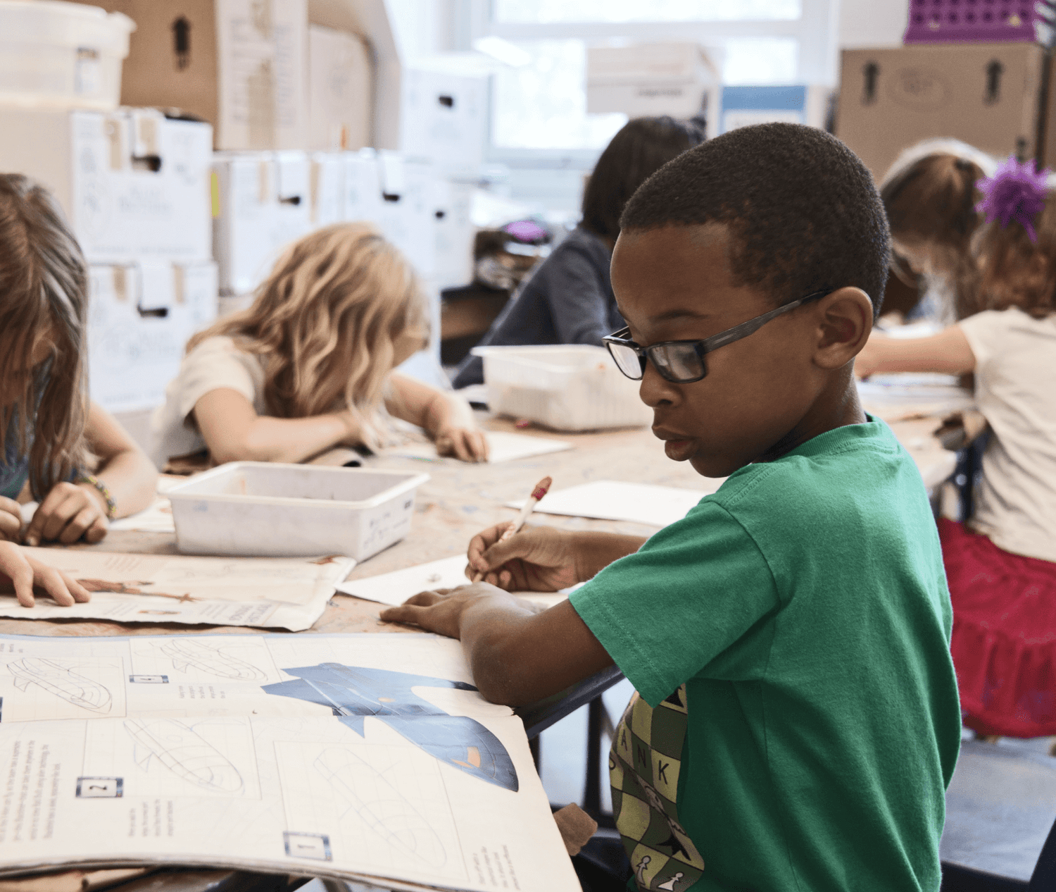 Plusieurs enfants sont assis et écrivent dans une salle de classe. L'enfant principal met des lunettes pour une meilleure vision.