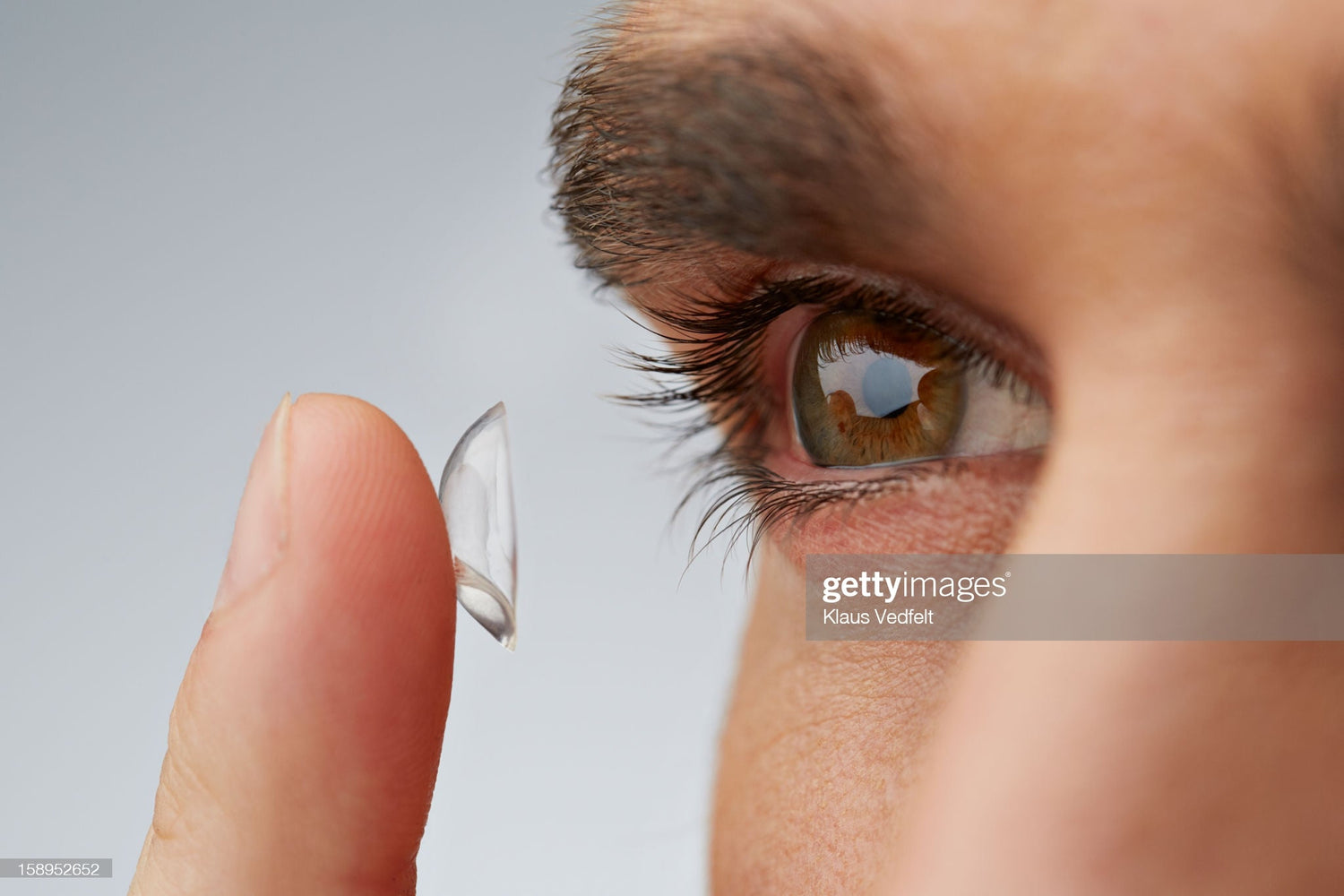 Un homme avec des lentilles de contact à ses doigts sur le point de le porter