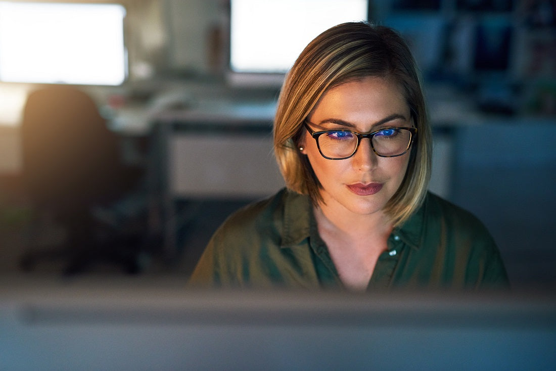 Une femme avec des lunettes bien enduites assise devant un ordinateur