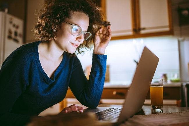 Une dame assise devant un ordinateur portable avec des lentilles spécialisées pour prévenir les malformations oculaires